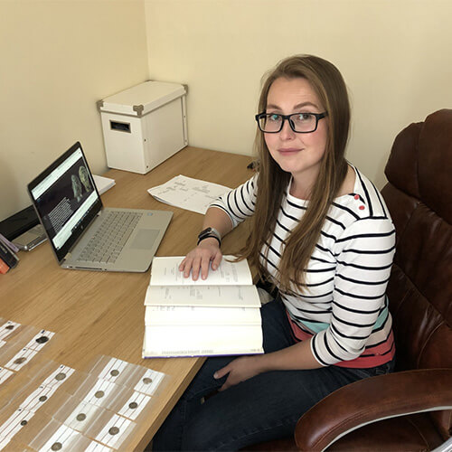 Eleanore Cox sitting at a desk cataloguing archaeological finds